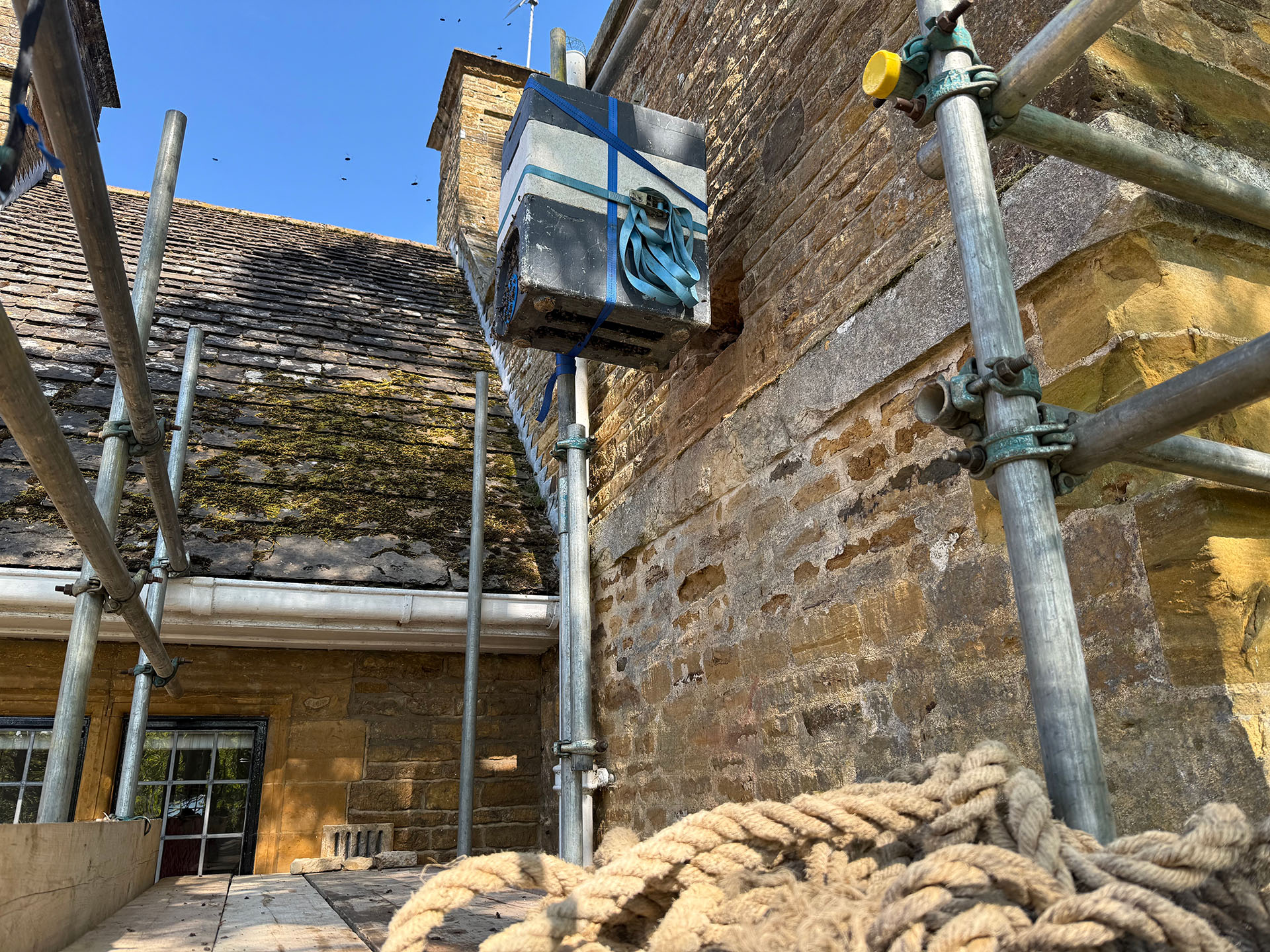 How Much Do Live Honeybee Removals From Buildings Cost? this image shows a live honeybee removal from a home. There is a scafffolding erected to the outside of the building with a nuc in place to house the bees