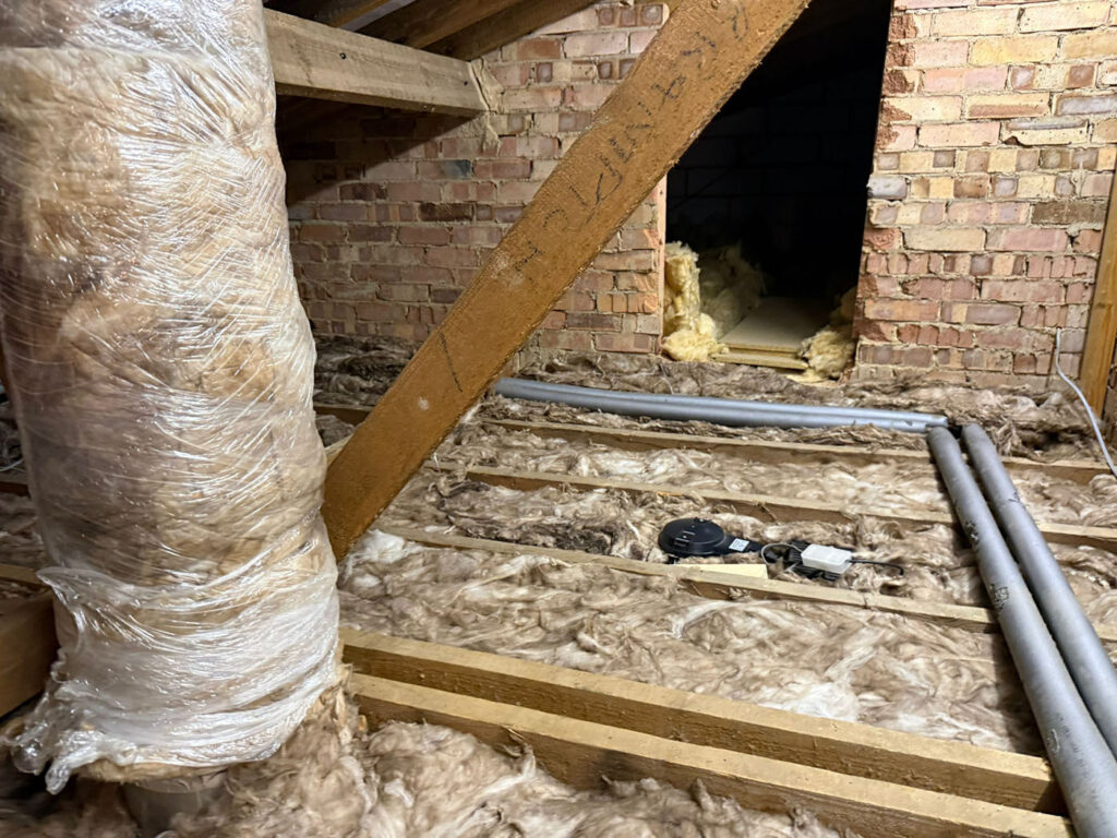 Contaminated loft insulation with exposed pipework following prolonged rat activity